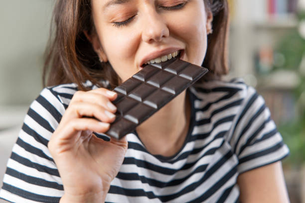 istock Young woman eating chocolate bar 1321677477