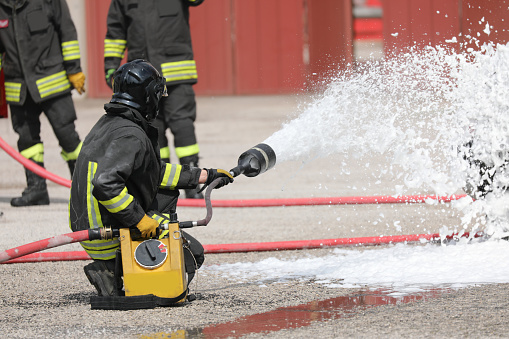 Firefighters using fire hose extinguishing burning fire