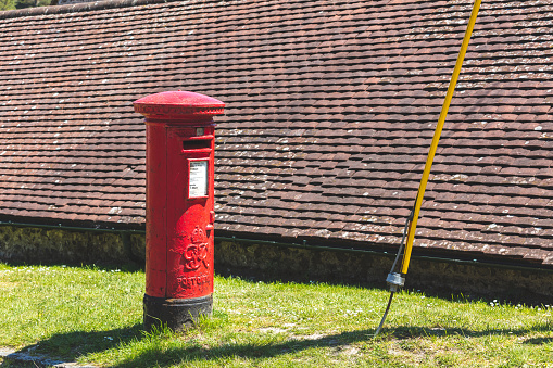 East Dean, UK - May 31, 2021: A bright red Royal Mail British postbox on the street
