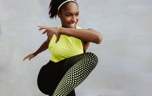 Female athlete in sportswear doing fitness workout. African woman doing stretching exercise and smiling.