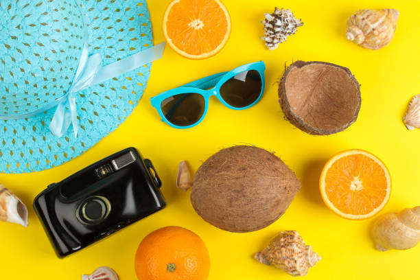 istock summer accessories with sun glasses, hat, shells, camera and coconut on a bright yellow background. top view. 1321684195