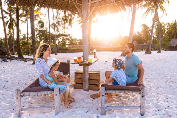 istock Happy family talking on deck chairs at the beach. 1321684258