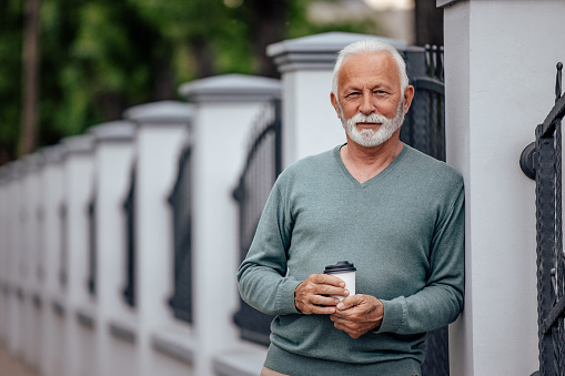 Portrait of a cheerful mature man, looking at camera, drinking coffee.