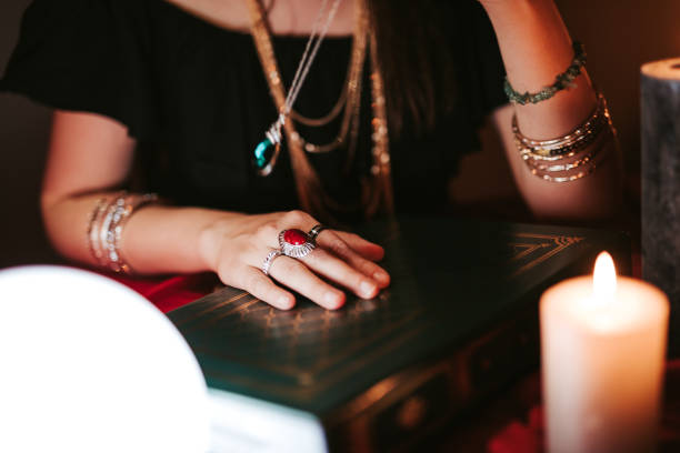 istock Fortune teller hand on book of charms 1321686583
