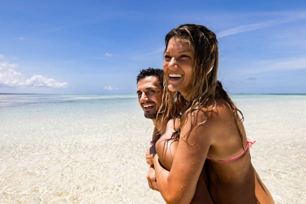 Happy couple having fun while piggybacking on the beach.
