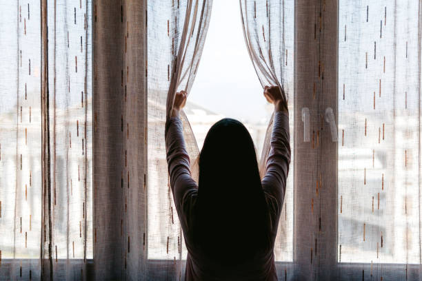 istock Woman opens the curtains at window 1321687530