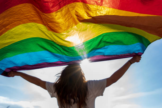 joven ondeando bandera lgbti - homosexual rainbow gay pride flag flag fotografías e imágenes de stock