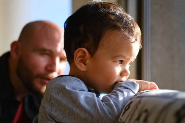 istock One baby boy with his father looking out the window. 1321689390