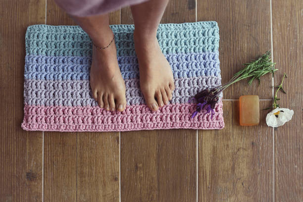 istock Bare feet of a woman on a bath mat with decorations 1321689711