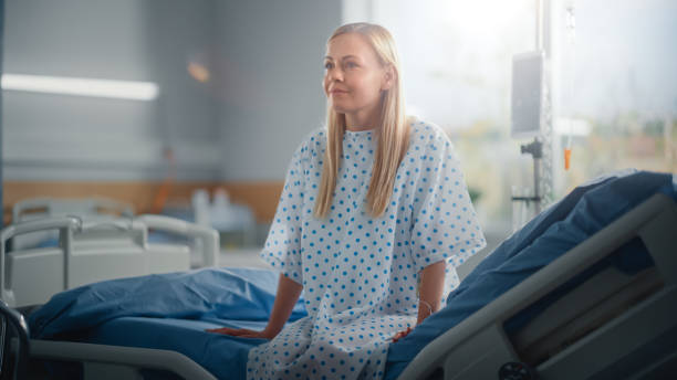 moderne krankenhausstation: schöne kaukasische patientin ruht auf einem bett, vollständig erholen nach erfolgreicher operation, krankheit oder coronavirus sie lächelt. hinter ihrem fenster mit einem schönen sonnigen blick - operating stock-fotos und bilder