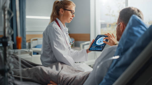 sjukhusavdelning: vänlig kvinnlig läkare pratar med sjuk manlig patient som vilar i sängen, använder tablettdator, visar och förklarar hjärnskanningsresultat. läkare pratar med en man som återhämtar sig efter operationen - brain scan' bildbanksfoton och bilder