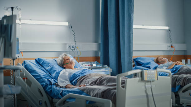 sala de hospital: hermosa anciana que usa máscara de oxígeno durmiendo en la cama, recuperándose completamente después de la enfermedad y la cirugía exitosa. mujer mayor soñando con su familia, amigos, vida feliz - patient room fotografías e imágenes de stock