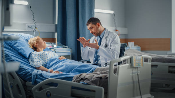 Hospital Ward: Friendly Doctor Talks to Smiling Young Woman Resting in Bed, Fully Recovering after Sickness. Physician Uses Tablet Computer, Does Checkup, Gives Treatment Advice, Health Recommendation Hospital Ward: Friendly Doctor Talks to Smiling Young Woman Resting in Bed, Fully Recovering after Sickness. Physician Uses Tablet Computer, Does Checkup, Gives Treatment Advice, Health Recommendation doctors surgery stock pictures, royalty-free photos & images