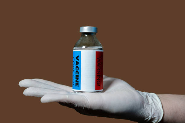 istock No vaccination for coronavirus. Vaccine side effects hazard concept. A hand holds a warning vial on the back. 1321699097