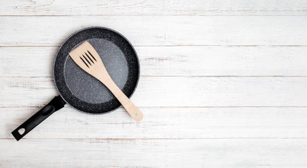 istock Frying pan with non-stick ceramic coating and spatula on a white wooden background. Cooking without sticking or oil. 1321699160