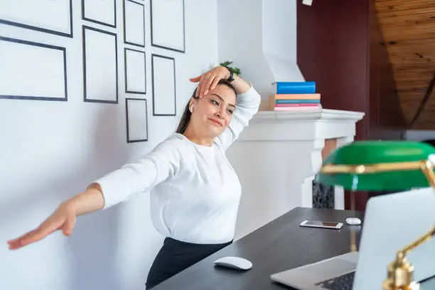 Photo of Young Woman Performing Exercises And Stretching In Front Of A Laptop Computer At Home Office