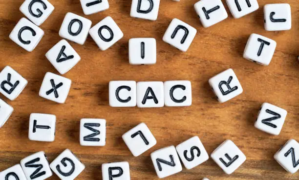 Photo of Small white and black bead cubes on wooden board, letters in middle spell CAC - Customer acquisition cost concept