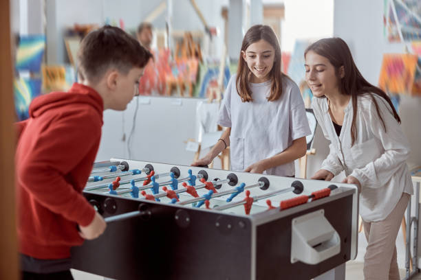 istock Elementary school kids in a classroom playing table football. Fun while recess at school 1321705286