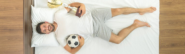 The man with a cup and a ball lay in the bed. view from above