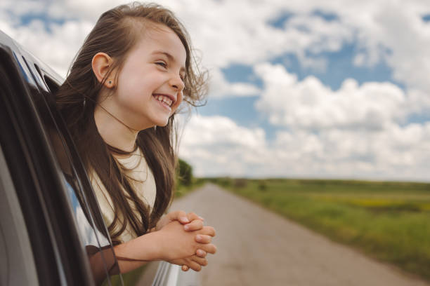 istock Little kid dreaming from an open car window while travelling. Summer trip with family 1321707854