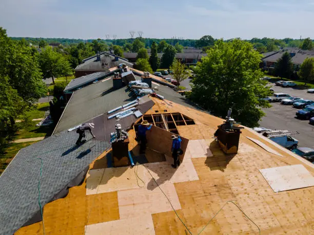 Roof shingles need with new shingles of an apartment building replacing a gray asphalt tile
