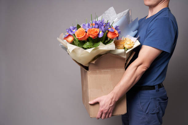 istock White male courier holding a large cardboard box with several bouquets 1321709770