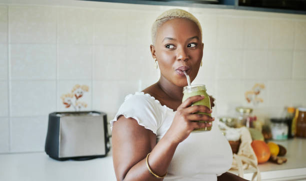 istock Young African woman drinking on a smoothie with a reusable straw 1321710489