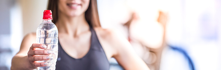 The woman hold a bottle of a water in the gym