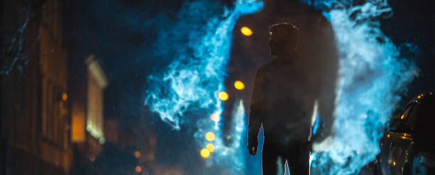 mężczyzna stoi w pobliżu chmury dymu. wieczorna noc - street fog profile zdjęcia i obrazy z banku zdjęć