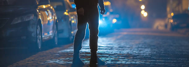 The man stand on the stone road. Evening night time. Telephoto lens shot The man stand on the stone road. Evening night time. Telephoto lens shot car street blue night stock pictures, royalty-free photos & images