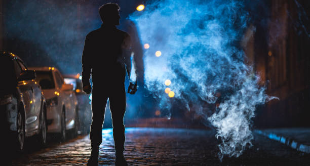 mężczyzna pali na ulicy. wieczorem po godzinie nocnej. zdjęcie teleobiektywu - street fog profile zdjęcia i obrazy z banku zdjęć