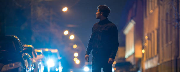 der mann steht auf der straße. abends nachtzeit. teleobjektivaufnahme - street fog profile stock-fotos und bilder