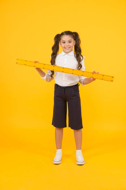istock Education and school concept. Sizing and measuring. Studying is fun. School adorable student study geometry. Kid school uniform hold ruler. Pupil cute girl with big ruler. Geometry school subject 1321712422