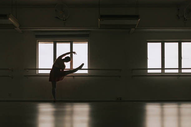 en silueta asiática adolescente china practicando danza de ballet levantar la pierna en barra en el estudio - estudio de ballet fotografías e imágenes de stock
