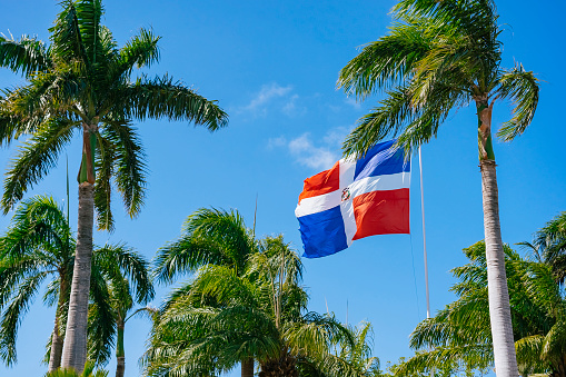 Flag of Dominican Republic waving in the wind against deep blue sky.