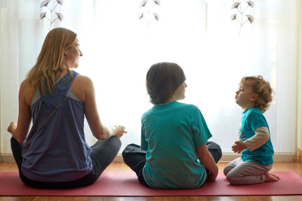 Mother and children doing meditation in the living room at home Mother and children doing meditation in the living room at home. Yoga in home mindfulness children stock pictures, royalty-free photos & images