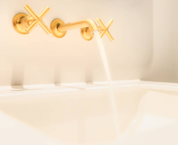 Golden taps and faucet flowing into bathroom basin