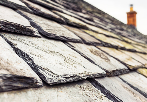 Signs of wear and weathering on the slate roof of a home.