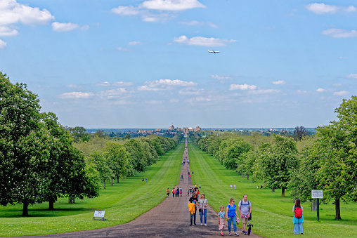 Plane over Windsor Castle viewed down the Long Walk with people enjoying the view and warm summer sun Windsor Berkshire United Kingdom - 31th of May 2021 - Travel destination UK