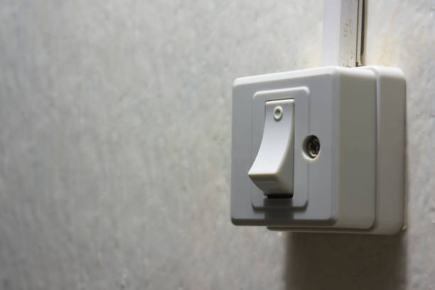 istock Light switch with sunlight and shadow on white wall with texture in the dark. Button in dim light. 1321720706