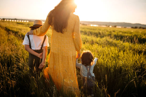 Carefree family Mother playing with kids meadow, it’s sunny and shiny yellow maternity dress stock pictures, royalty-free photos & images