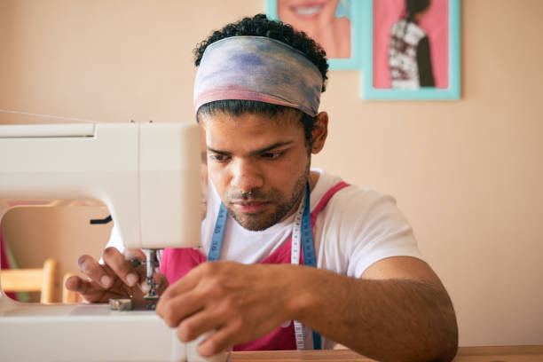 istock Shot of a handsome young tailor sitting alone in his studio and threading the needle in his sewing machine 1321722056