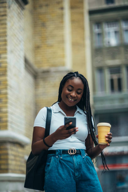 istock African american woman using smartphone and drinking coffee takeaway 1321722219