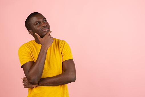 Remember all. Let me think. Doubt concept. Doubtful, thoughtful african man remembering something. Hunan emotions, facial expression concept. Studio. Isolated on trendy pink color