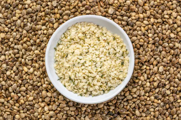 hemp seed hearts in a small ceramic bowl against a background of dry seeds, superfood and healthy eating