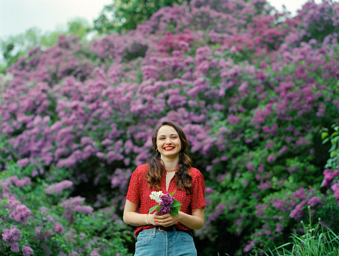 Portrait of young Caucasian woman on the background of blooming lilac, Camera film