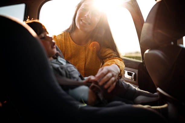istock Mother tightening seatbelt for kind on back seat 1321724539