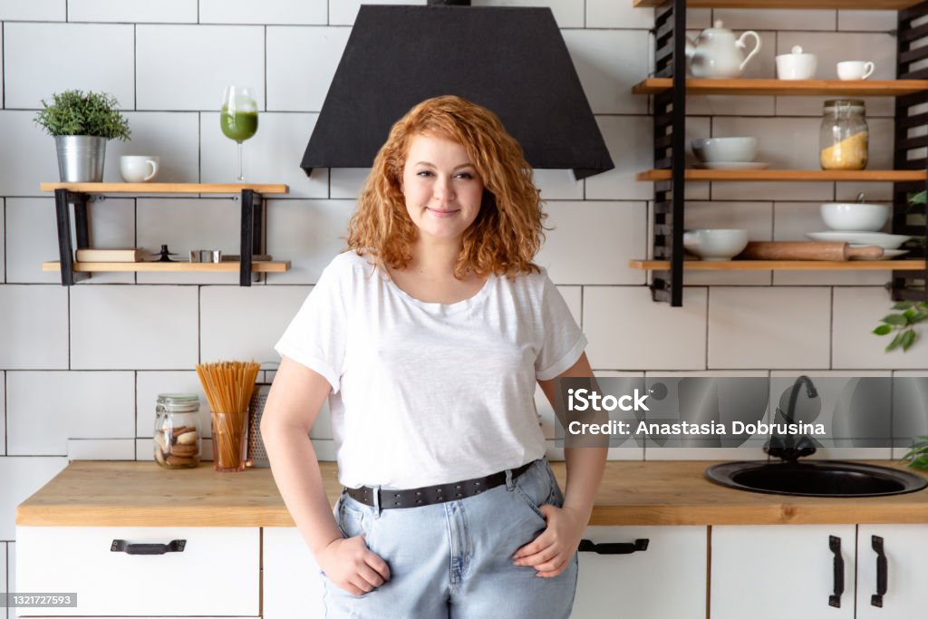 Portrait of a beautiful woman in kitchen Red head woman portrait. One Woman Only Stock Photo