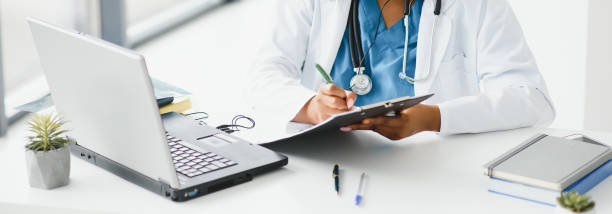 African doctor wear headset consult patient make online webcam video call on laptop screen. Telemedicine videoconference remote computer app virtual meeting. Over shoulder video call view. médico africano usar auriculares consultar paciente hacer videollamada webcam en línea en la pantalla del ordenador portátil. telemedicina videoconferencia remota de la aplicación informática de reunión virtual. vista de videollamada sobre el hombro.