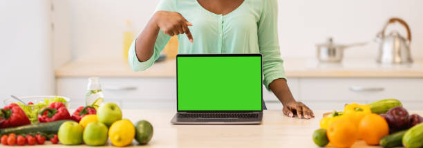 istock African female showing laptop empty screen standing in kitchen indoors 1321728199